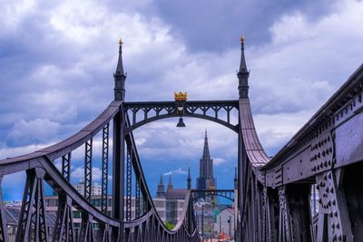 Low angle view of bridge against cloudy sky