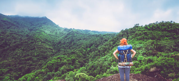 Rear view of man standing on mountain against sky