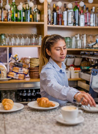 Portrait of young woman preparing food at table