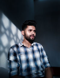 Portrait of young man standing against wall