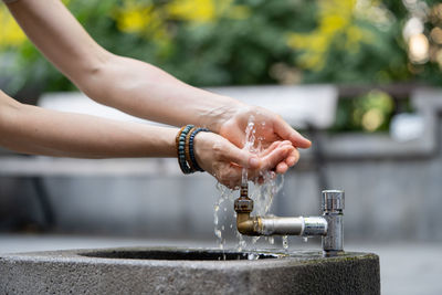 Hydration and aqua balance regulation for health. hands with water pouring from tap in street.