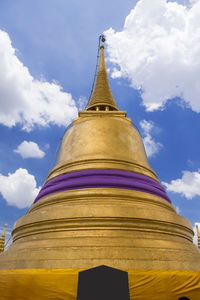 Low angle view of gold stupas against sky