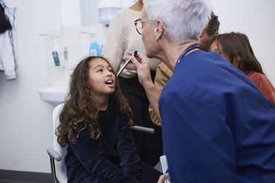 Female doctor checking girls throat