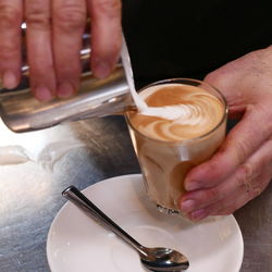 Midsection of man holding coffee cup on table