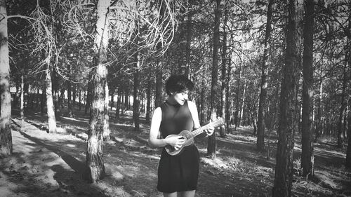 Woman playing guitar in forest