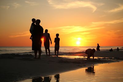Silhouette people on beach during sunset