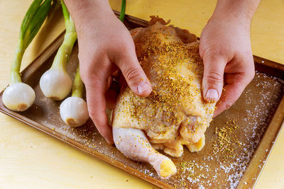 Cropped hands marinating chicken on table