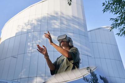 Low angle view of woman holding modern building