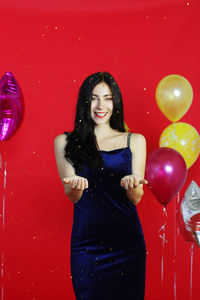 Portrait of a smiling young woman with red balloons