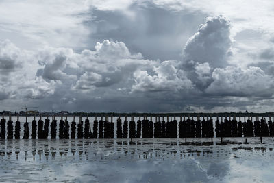 Wooden posts in lake against sky