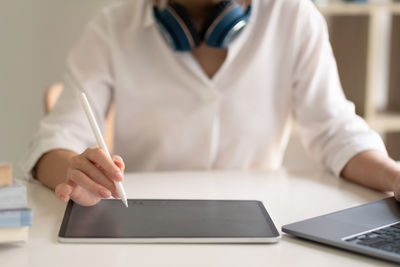 Midsection of woman using mobile phone on table