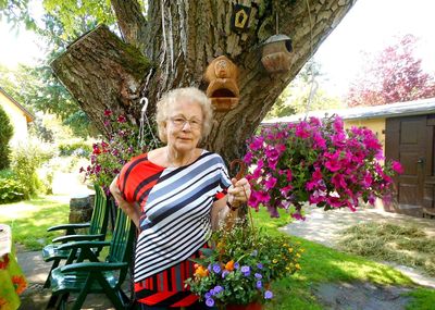 Portrait of young woman sitting on tree trunk