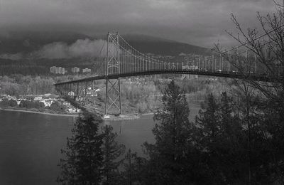 Bridge over river against sky in city