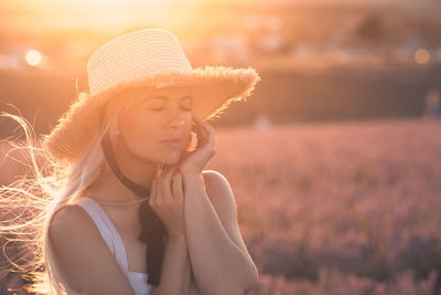Woman wearing hat on field during sunset