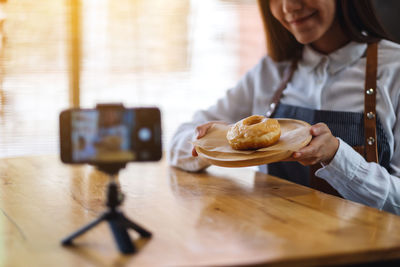 Midsection of woman using mobile phone on table