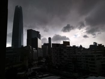 Buildings in city against storm clouds