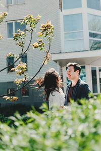 Side view of smiling couple looking at each other while standing against building