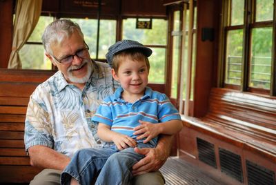 Grandfather with cute grandson sitting on bench