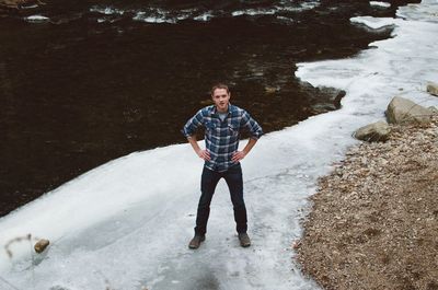 Portrait of man standing on ice by river