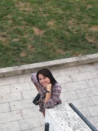 High angle portrait of a smiling young woman on footpath