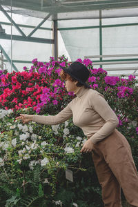 A beautiful plus size girl in a hat laughs among the green plants of greenhouse