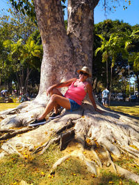 Woman sitting on tree trunk