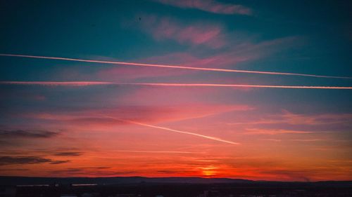 Low angle view of vapor trails in sky during sunset