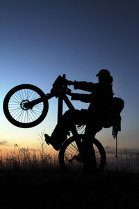 Silhouette man riding bicycle on field at night