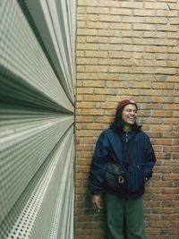 Portrait of smiling man standing against brick wall