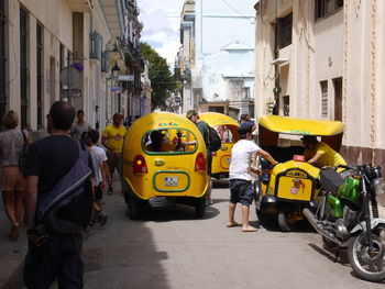 People and vehicle on street amidst buildings