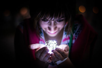 Close-up of mid adult woman looking at illuminated string lights