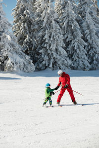 Full length of father and son skiing on snow during winter