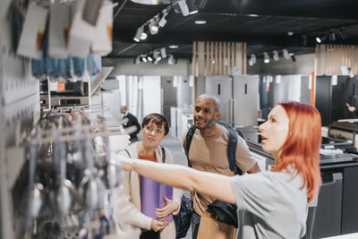 Saleswoman advising customers in buying modern appliance at electronics store