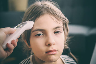 Mother examining daughter with thermometer