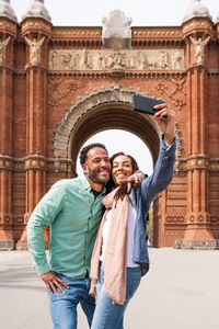 Portrait of young woman standing against historic building