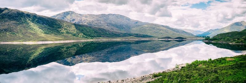 Lake in scotland with very still water reflecting the scenic mountains of the landscape