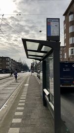 People at railroad station in city against sky