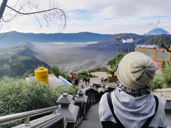 Rear view of people looking at mountains against sky