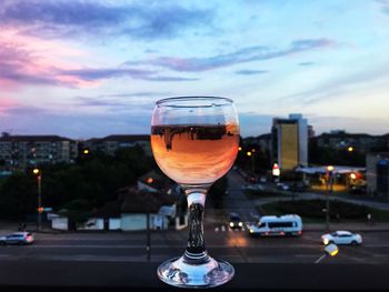 Close-up of beer in glass against sky at sunset