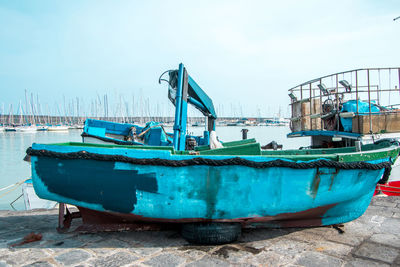 Fishing boats moored at harbor against sky