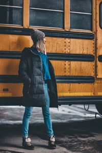 Young woman standing against bus