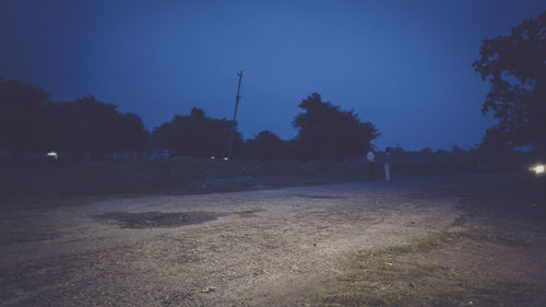 Street amidst field against clear sky at night