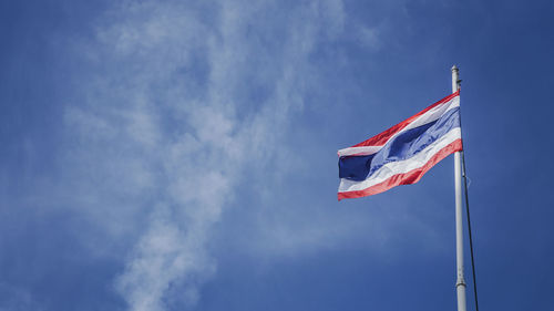 Low angle view of thai flag waving against blue sky