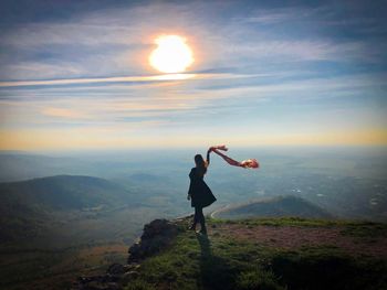 Woman on top of the mountain holding a scarf floating in the wind