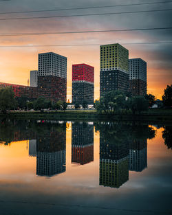 Reflection of buildings in lake against sky during sunset