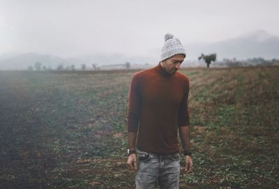 Man wearing sweater standing on field during winter