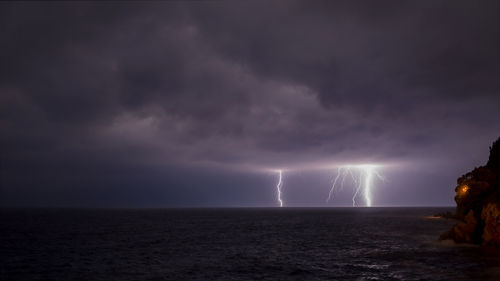 Scenic view of sea against storm clouds at night