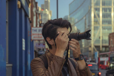 Close-up of man photographing while standing in city