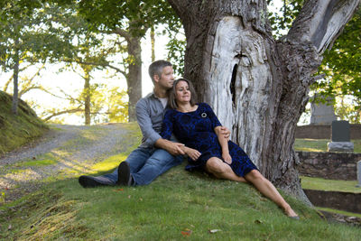 Full length of couple sitting on tree trunk