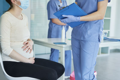 Midsection of female doctor examining pregnant woman